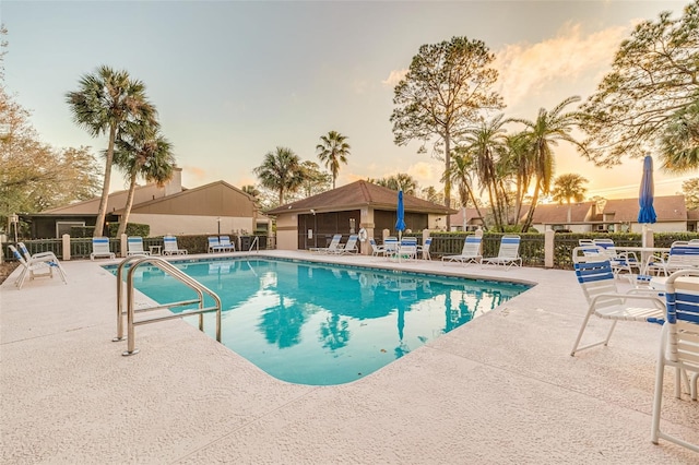 pool at dusk featuring a patio area