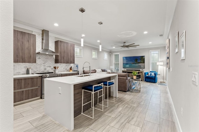 kitchen with tasteful backsplash, modern cabinets, stainless steel electric stove, light countertops, and wall chimney range hood