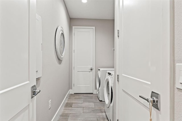 laundry area featuring laundry area, wood tiled floor, baseboards, and washing machine and clothes dryer