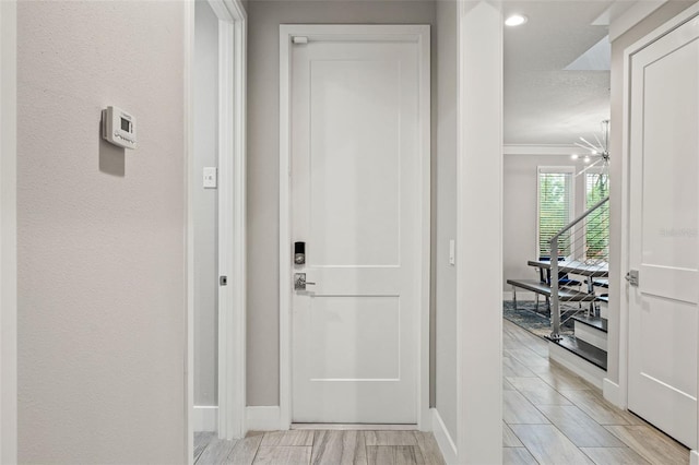 interior space with a textured wall, an inviting chandelier, ornamental molding, wood tiled floor, and baseboards