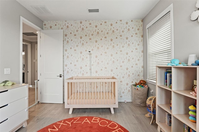 bedroom featuring wood finished floors, visible vents, and wallpapered walls