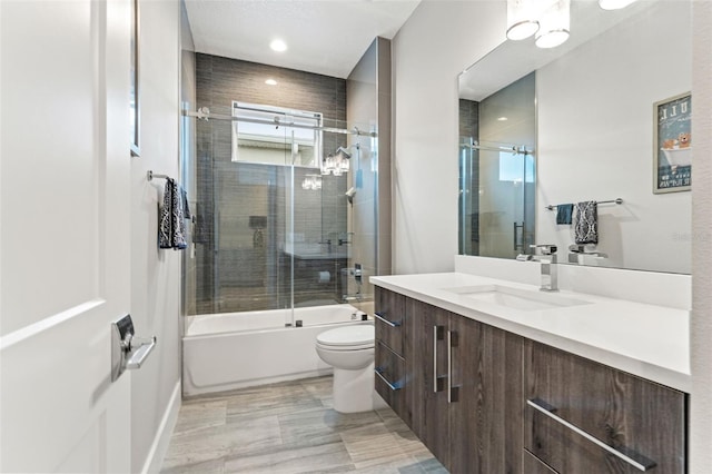 bathroom featuring enclosed tub / shower combo, vanity, and toilet