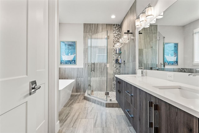 bathroom featuring double vanity, a soaking tub, a shower stall, and a sink