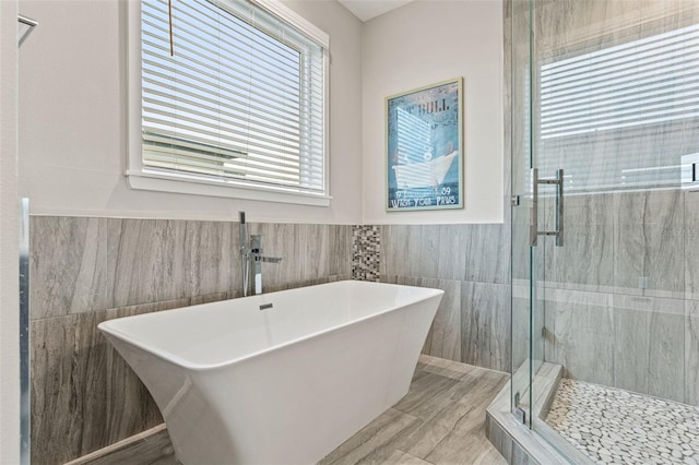 full bathroom with a soaking tub, a shower stall, tile walls, and a wainscoted wall