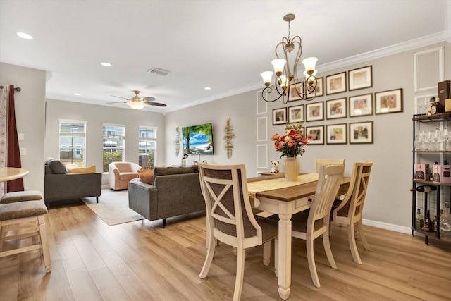 dining area with ornamental molding, ceiling fan with notable chandelier, and light wood-type flooring