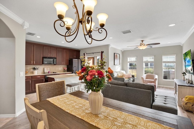 dining room with ornamental molding, ceiling fan with notable chandelier, and light wood-type flooring