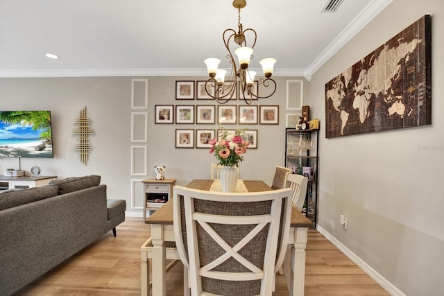 dining room with a notable chandelier, crown molding, and light wood-type flooring