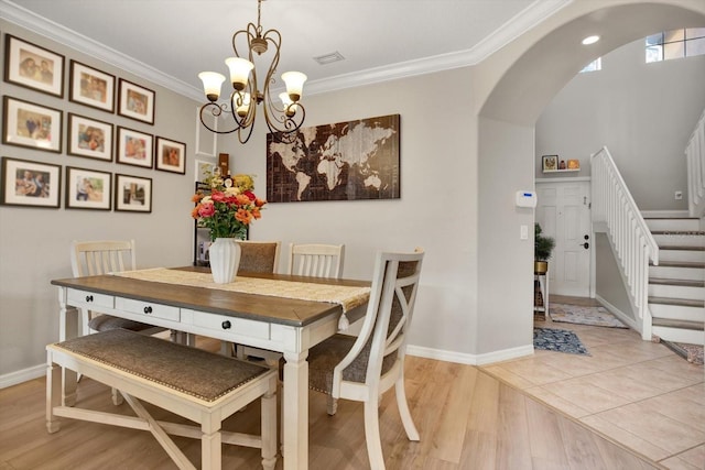 dining room with crown molding, an inviting chandelier, and light wood-type flooring