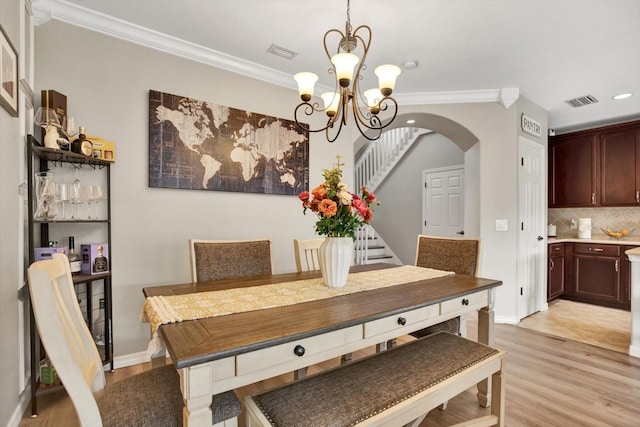 dining space with crown molding, a chandelier, and light hardwood / wood-style flooring