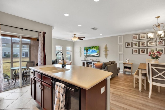 kitchen with sink, crown molding, light hardwood / wood-style flooring, an island with sink, and pendant lighting