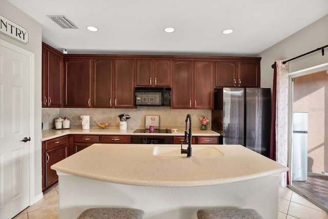 kitchen featuring light tile patterned floors, backsplash, and black appliances