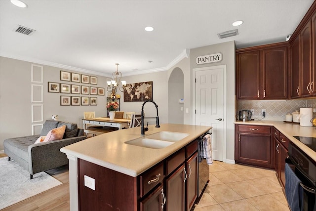 kitchen featuring sink, crown molding, a center island with sink, pendant lighting, and backsplash