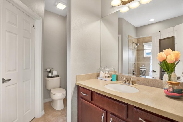 bathroom featuring vanity, tiled shower, tile patterned floors, and toilet