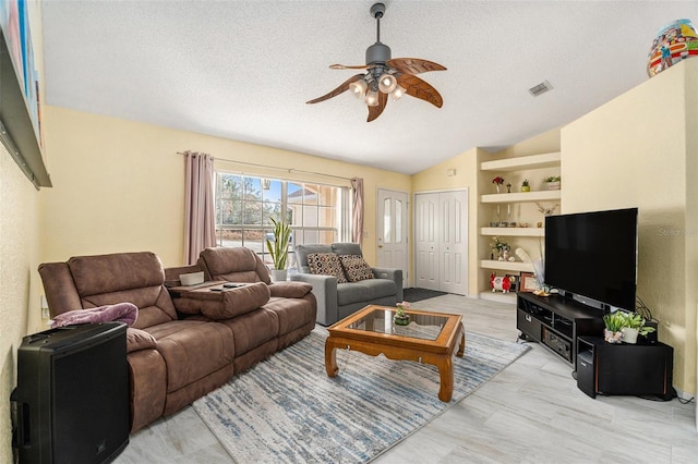 living room featuring ceiling fan, built in shelves, vaulted ceiling, and a textured ceiling