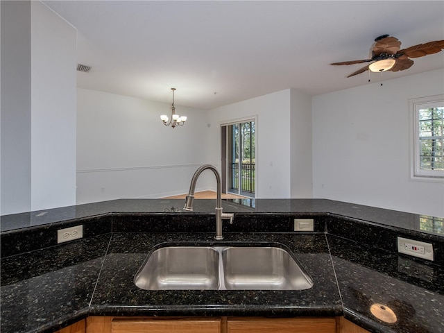 kitchen with hanging light fixtures, sink, and dark stone countertops