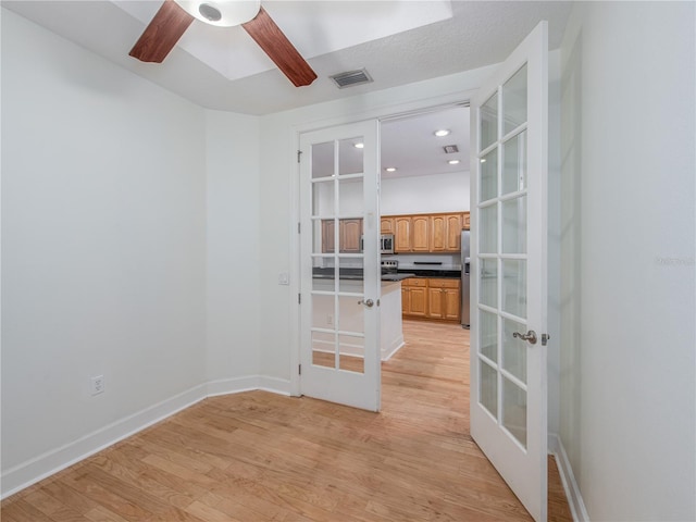 empty room with light hardwood / wood-style flooring, ceiling fan, and french doors