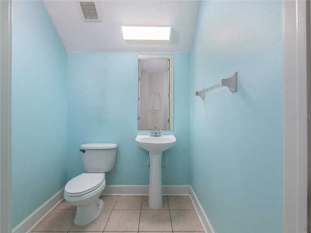 bathroom with a textured ceiling, tile patterned floors, and toilet