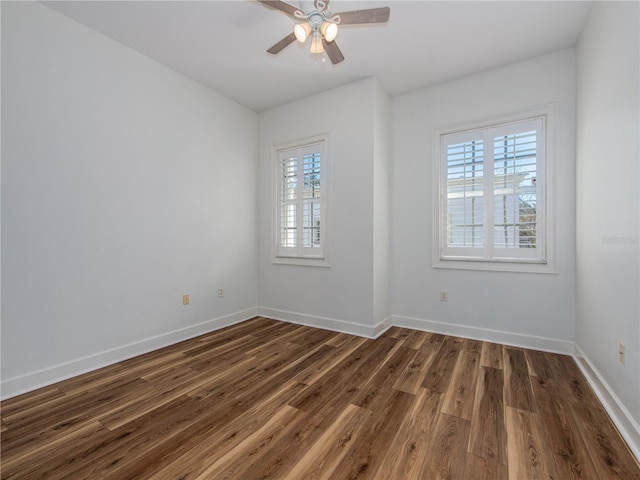 empty room with ceiling fan, a healthy amount of sunlight, and dark hardwood / wood-style floors