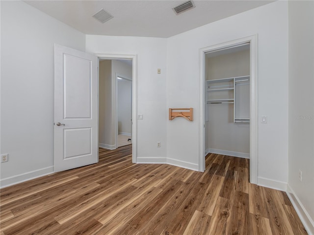 unfurnished bedroom featuring dark hardwood / wood-style flooring, a spacious closet, and a closet