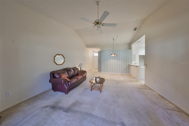 carpeted living room with ceiling fan, vaulted ceiling, and a textured ceiling