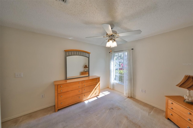 unfurnished bedroom with a textured ceiling, light colored carpet, and ceiling fan