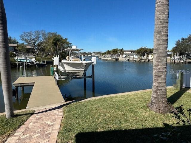 view of dock with a lawn and a water view