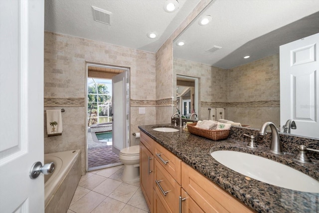 bathroom featuring tile patterned floors, toilet, tile walls, a textured ceiling, and vanity