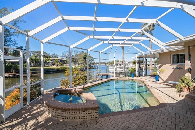 view of pool featuring a patio, an in ground hot tub, a water view, and glass enclosure