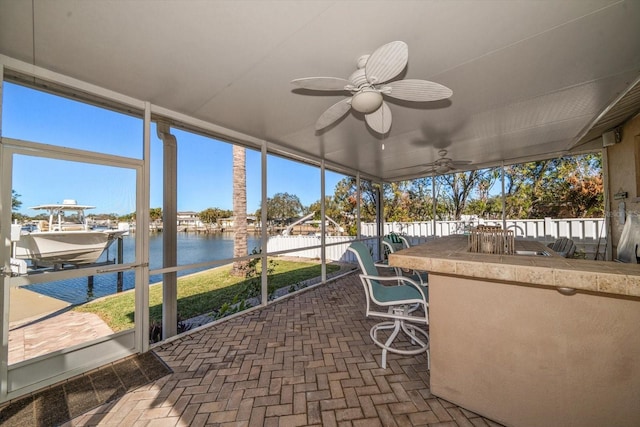 sunroom / solarium with a water view and ceiling fan