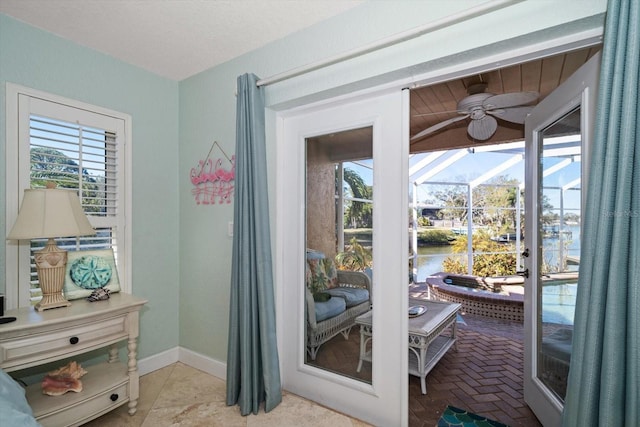 doorway to outside with ceiling fan and a water view