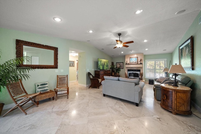 living room featuring ceiling fan, lofted ceiling, and a fireplace