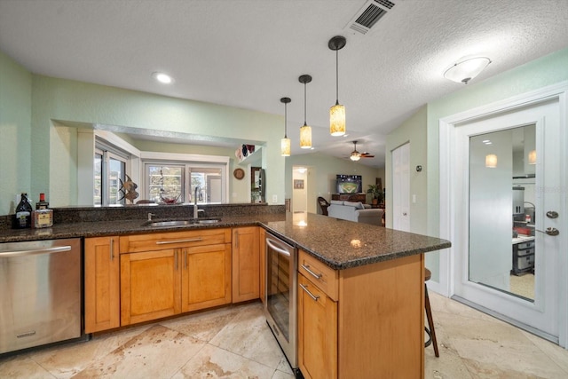 kitchen featuring decorative light fixtures, sink, stainless steel dishwasher, and kitchen peninsula