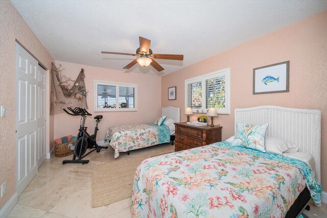 bedroom with multiple windows, ceiling fan, and a closet