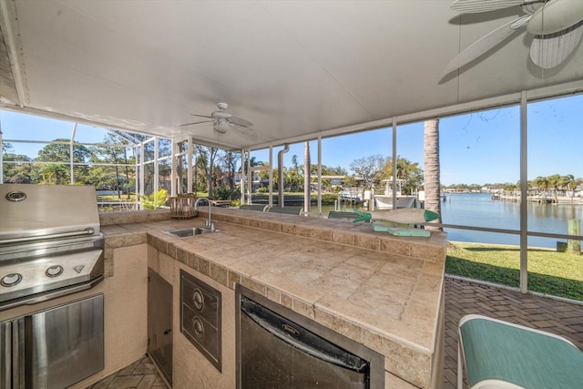 sunroom / solarium featuring a healthy amount of sunlight, a water view, sink, and ceiling fan