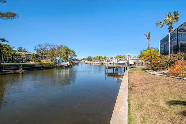 dock area featuring a water view, a yard, and glass enclosure