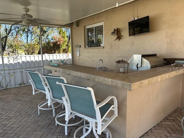 view of patio with exterior kitchen, ceiling fan, and an outdoor wet bar