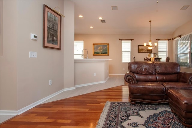 living room featuring a notable chandelier, light hardwood / wood-style floors, and sink