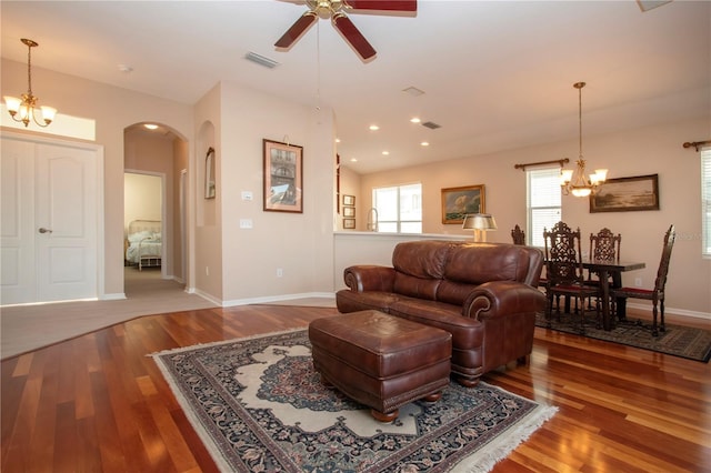 living room featuring ceiling fan with notable chandelier and wood-type flooring