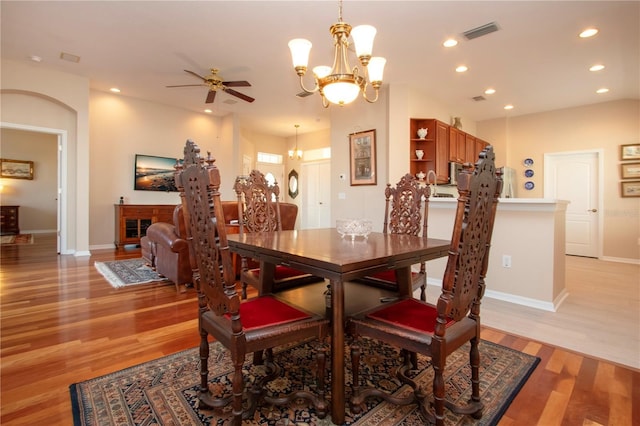 dining room featuring ceiling fan with notable chandelier and light hardwood / wood-style flooring