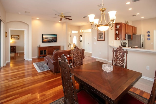 dining space featuring ceiling fan with notable chandelier and light hardwood / wood-style flooring