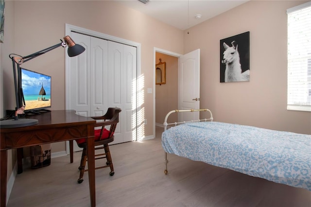 bedroom with light hardwood / wood-style floors and a closet