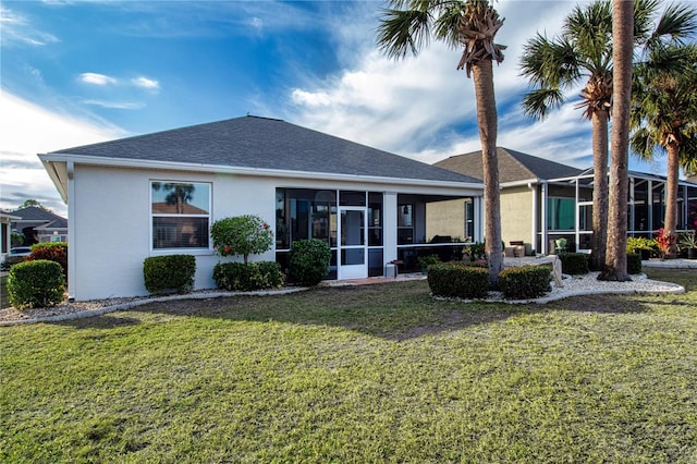 rear view of property featuring a lawn and a sunroom