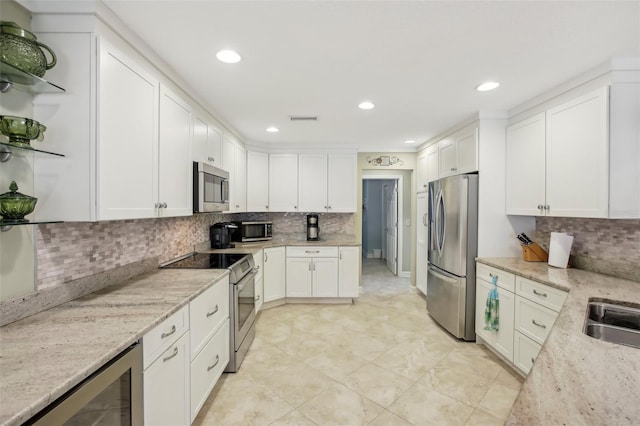 kitchen featuring stainless steel appliances, white cabinets, beverage cooler, and light stone counters