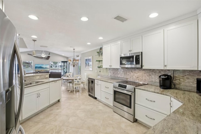 kitchen with white cabinetry, stainless steel appliances, light stone counters, wine cooler, and decorative light fixtures