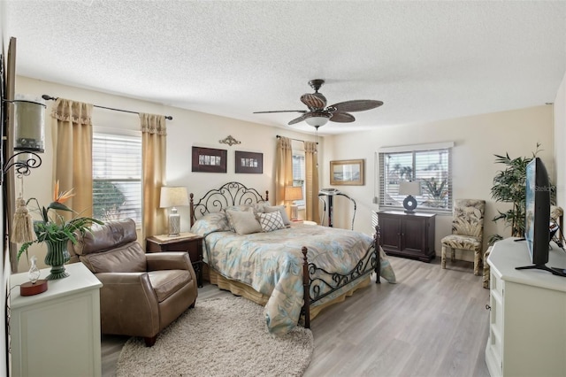 bedroom featuring ceiling fan, a textured ceiling, and light wood-type flooring