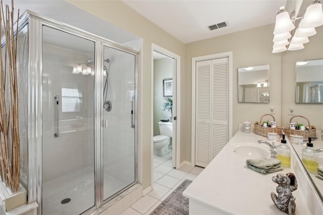 bathroom featuring a shower with door, vanity, tile patterned floors, and toilet