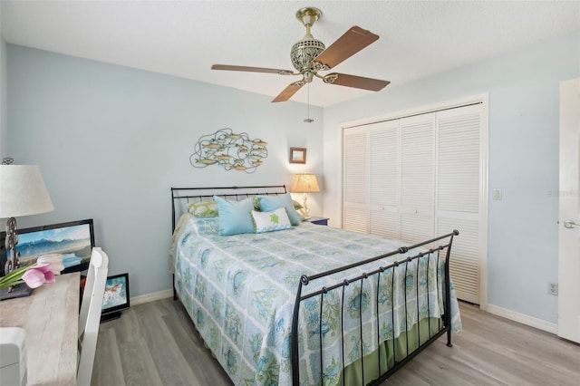 bedroom with wood-type flooring, ceiling fan, and a closet