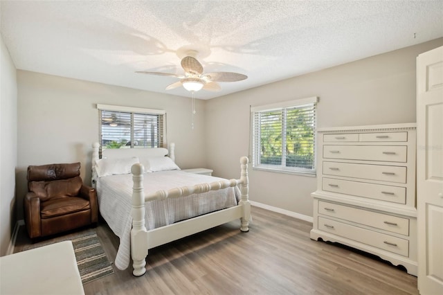 bedroom with multiple windows, ceiling fan, hardwood / wood-style flooring, and a textured ceiling