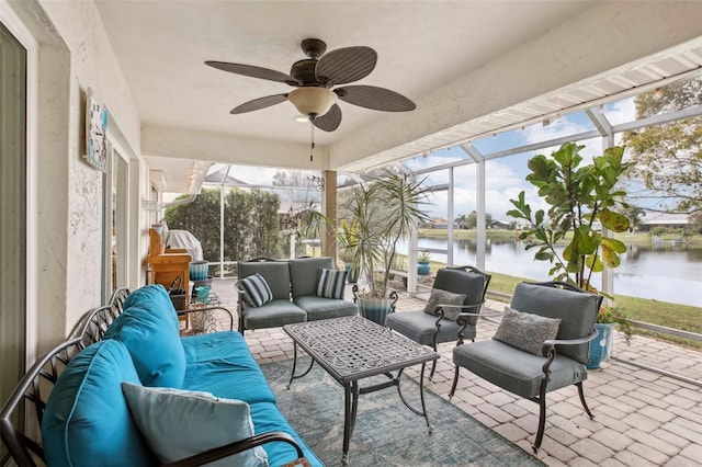 sunroom featuring ceiling fan and a water view