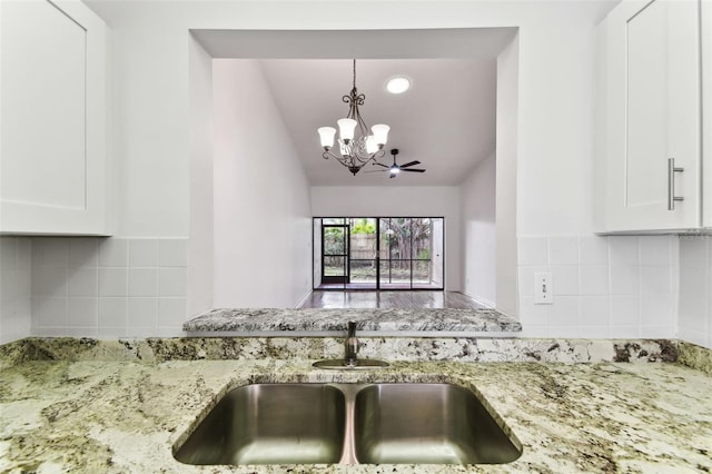 kitchen featuring white cabinetry, sink, light stone counters, and decorative backsplash